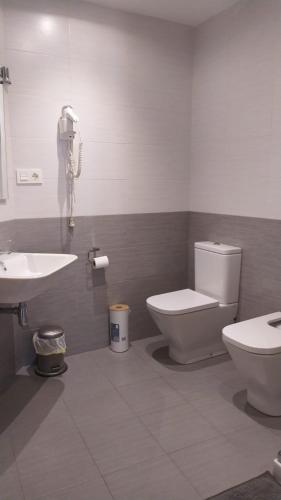 a bathroom with a toilet and a sink and a phone at Pensión Manoli in Bilbao