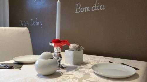 B&B Aria d'Argento & Relax Home في ترينتو: طاولة عليها صحون بيضاء وشمعة