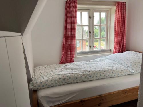 una camera con letto e finestra con tende rosse di Finkenhof-Wohnung-Tulpe ad Archsum