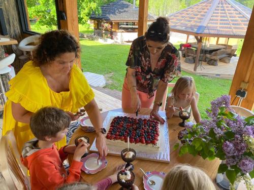 a woman and children sitting at a table with a cake at Neitsijärve majutus in Otepää