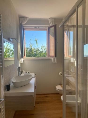 ein Bad mit einem Waschbecken, einem WC und einem Fenster in der Unterkunft Podere Belsogno-Camera Lavanda in Montalcino