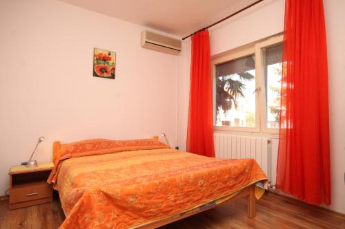 a bedroom with a bed and a window with red curtains at Apartments with a swimming pool Valbandon, Fazana - 7257 in Marana