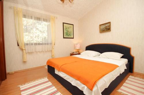 a bedroom with a large bed with an orange blanket at Apartments with a parking space Liznjan, Medulin - 7224 in Ližnjan