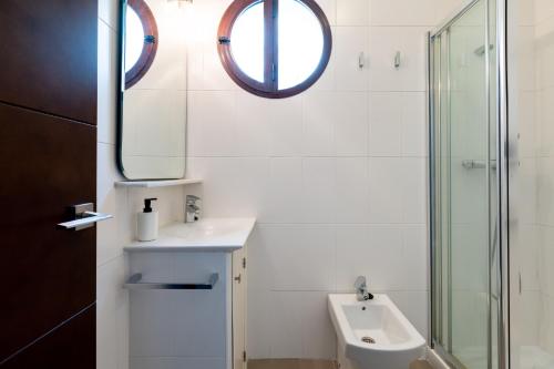 biała łazienka z umywalką i lustrem w obiekcie Holi-Rent Cuna w Sewilli