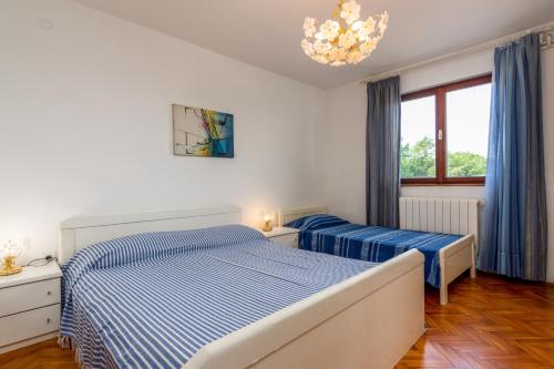 Un dormitorio con dos camas y una lámpara de araña. en Family friendly apartments with a swimming pool Sisan, Medulin - 7243, en Šišan