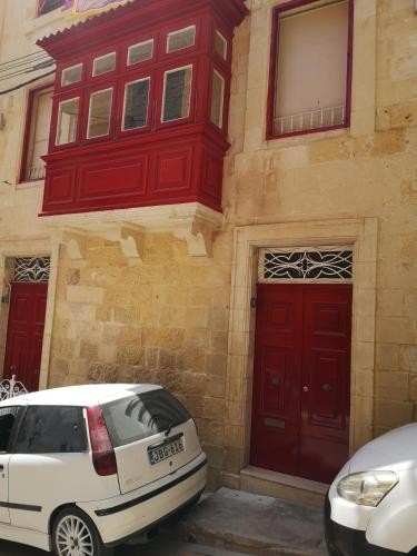 a white car parked in front of a building with red doors at Two gate town house in Senglea