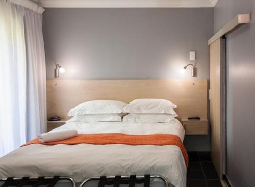 1 dormitorio con 1 cama grande con almohadas blancas en Rose Lodge, en Ciudad del Cabo