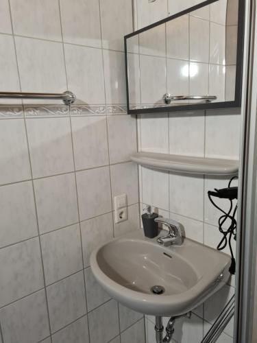 a white bathroom with a sink and a mirror at Zum Goldenen Fass in Nassau