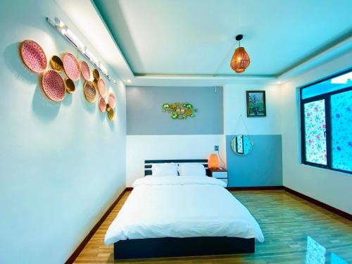 - une chambre avec un lit blanc et des murs bleus dans l'établissement Ti Lau Homestay & Motorbikes, à Ha Giang