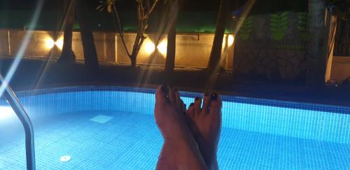 a person with their feet in a swimming pool at GR STAYs Private Pool Villa in Calangute 5 mins to Baga in Arpora