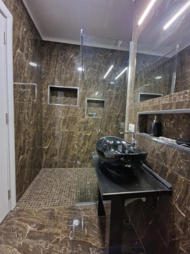 baño con lavabo negro sobre una mesa negra en Absolut Vollga, en Durrës