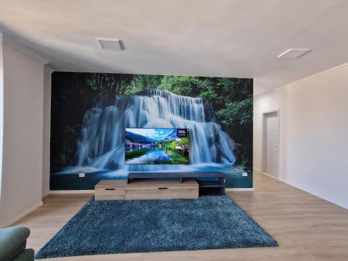 a tv in a living room with a waterfall mural at Absolut Vollga in Durrës