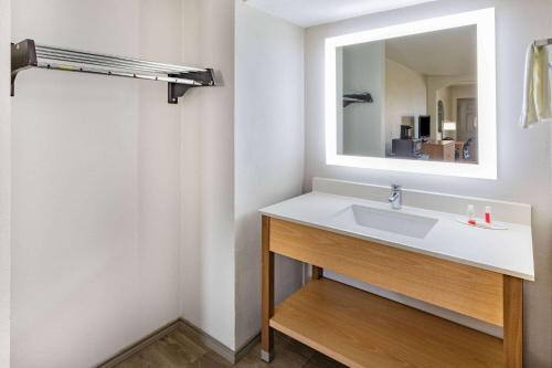 a bathroom with a sink and a mirror at Days Inn & Suites by Wyndham Huntsville in Huntsville