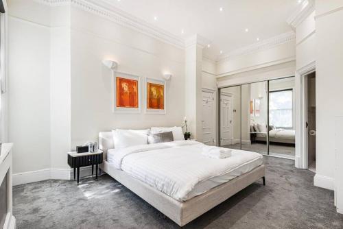 a white bedroom with a large bed and a mirror at The Redington Royal in London
