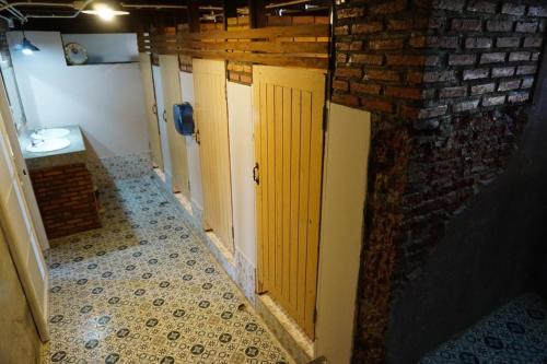 rząd drzwi w łazience z ceglaną ścianą w obiekcie Insight Hostel w mieście Chiang Mai