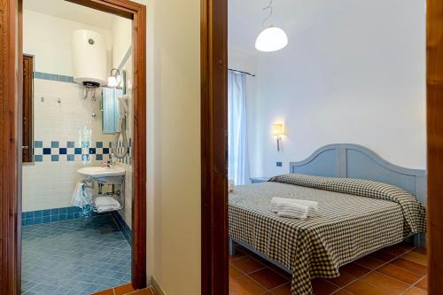 a bedroom with a bed and a bathroom with a sink at Villaggio Cala Mancina in San Vito lo Capo