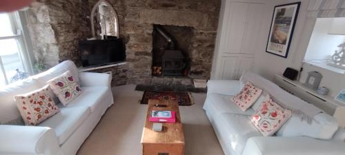 a living room with two white couches and a fireplace at Samphire Cottage in Helston