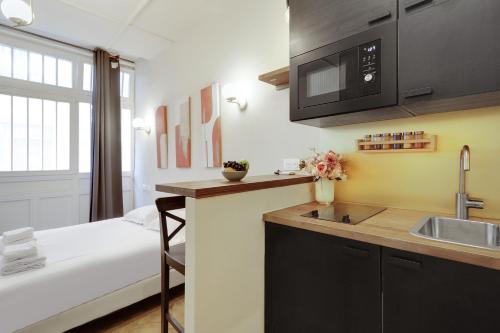 - une cuisine avec évier et un lit dans une chambre dans l'établissement Cozy studio - 2P - Gare de l'Est, à Paris