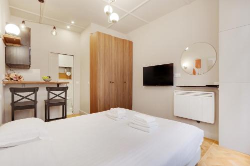 Biała sypialnia z białym łóżkiem i kuchnią w obiekcie Cozy studio - 2P - Gare de l'Est w Paryżu