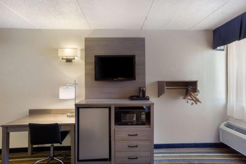 a room with a desk and a tv on a wall at Quality Inn Albany Colonie in Albany