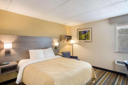 a hotel room with a bed and a desk and a window at Quality Inn Albany Colonie in Albany