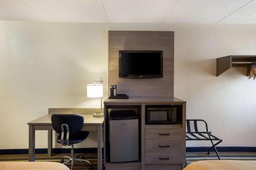 a hotel room with a desk and a tv on a wall at Quality Inn Albany Colonie in Albany