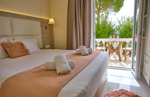 a bedroom with two beds and a balcony with a table at Katoi Studios Agios Georgios Pagoi in Agios Georgios Pagon