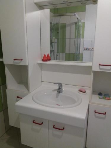 une salle de bain blanche avec un lavabo et un miroir dans l'établissement Appartement meublé agréable au cœur du massif du Jura, à Malpas