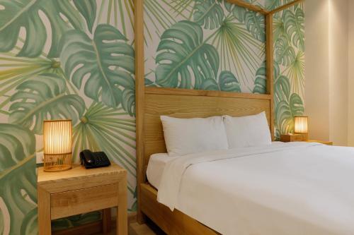 a bedroom with a bed with a tropical wallpaper at Super OYO Capital O 1169 Le Grand Hanoi Hotel - The Charm in Hanoi