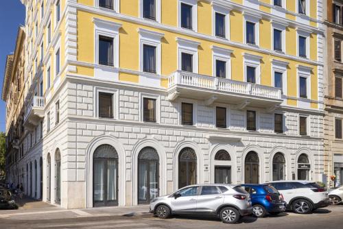 un bâtiment jaune et blanc avec des voitures garées devant lui dans l'établissement Generator Rome, à Rome