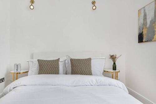 1 dormitorio blanco con 1 cama blanca y 2 mesitas de noche en Lady on the Lane- 2 bed Primrose Hill, en Londres