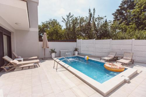 una piscina en un patio trasero con sillas y un patio en Mi Casa 2, en Vrdnik