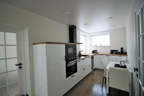 a kitchen with white cabinets and a stove top oven at BAM apartments in Palanga