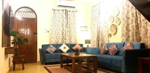 a living room with a blue couch and a table at GR STAYs Private Pool Villa in Calangute 5 mins to Baga in Arpora