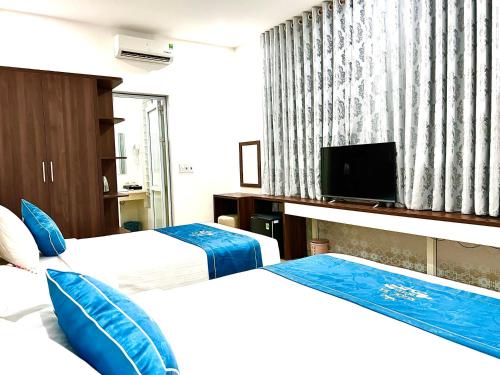 a hotel room with two beds and a television at Khách sạn Ngọc Hà in Lao Cai