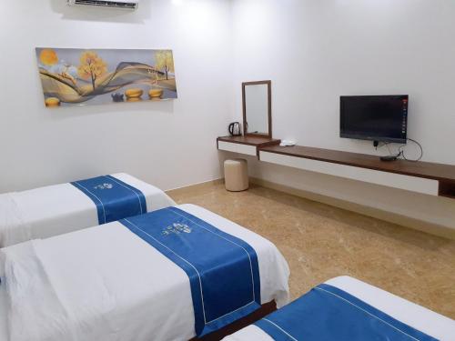 a room with two beds and a flat screen tv at Khách sạn Ngọc Hà in Lao Cai