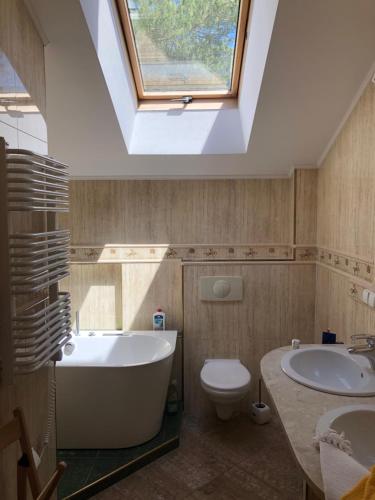 a bathroom with a tub and a toilet and a skylight at Dom letniskowy Dorota in Poddąbie