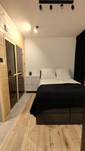 a bedroom with a bed with a black blanket on it at Apartament 67 in Brzeziny