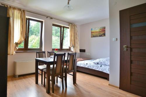 - une salle à manger avec une table, des chaises et un lit dans l'établissement Villa Asturia, à Rymanów-Zdrój
