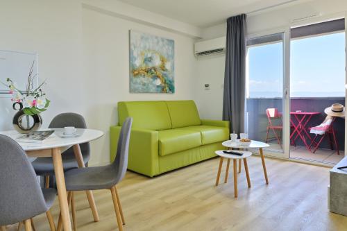 a living room with a green couch and tables at Résidence Easy Lodge in Ajaccio