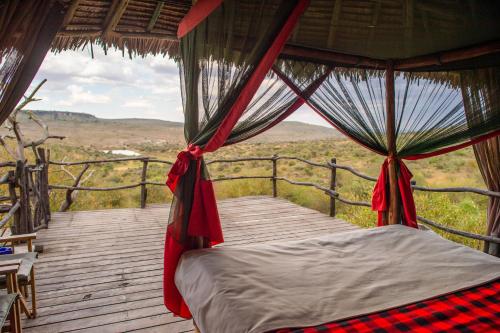 - une chambre avec un lit sur une terrasse en bois dans l'établissement Loisaba Star Beds, à Tura