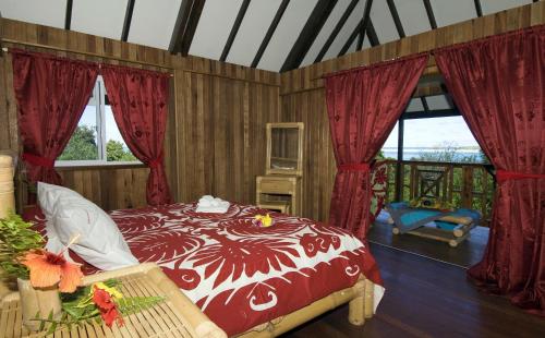 1 dormitorio con cama y ventanas de color rojo y blanco en Pension Vaimano-Raivavae, en Vaiuru