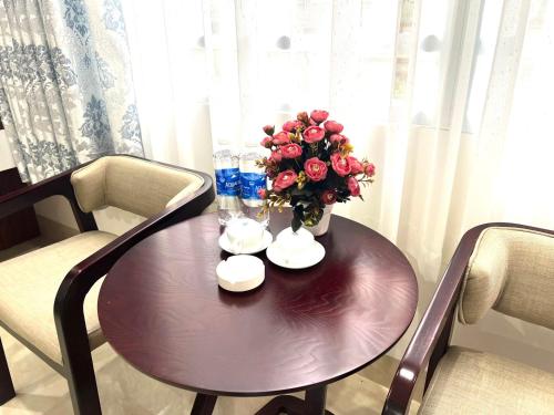 a wooden table with a vase of flowers on it at Khách sạn Ngọc Hà in Lao Cai