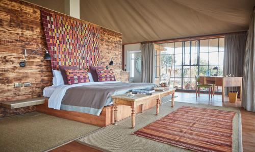 1 dormitorio con 1 cama y pared de madera en Loisaba Lodo Springs en Tura