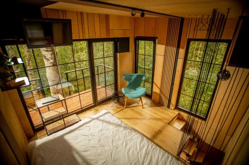 a room with a blue chair in a room with windows at Domek na drzewie - Na Łośmiu Metrach in Grudki