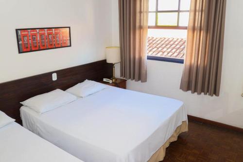 a hotel room with two beds and a window at Hotel Londres in São Lourenço