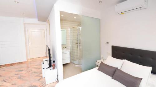 um quarto com uma cama branca e um chuveiro em Apartamentos Romana Playa 203 em Marbella