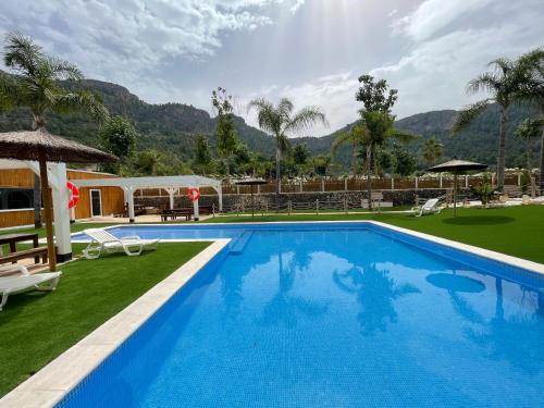 a large swimming pool with a resort with mountains in the background at Camping la escalada in Gandía