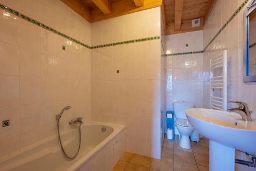 a bathroom with a tub and a sink and a toilet at Chalet Hibou in Les Gets