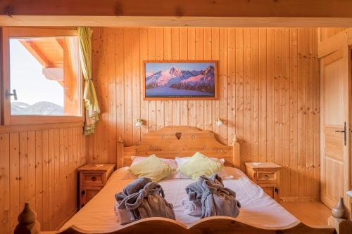 ein Schlafzimmer mit einem Bett in einer Holzwand in der Unterkunft Chalet Hibou in Les Gets